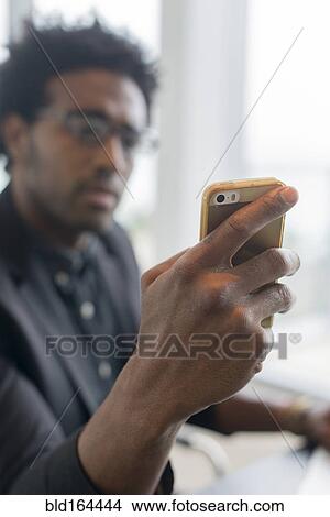 Picture - Hispanic businessman using cell phone in office. Fotosearch