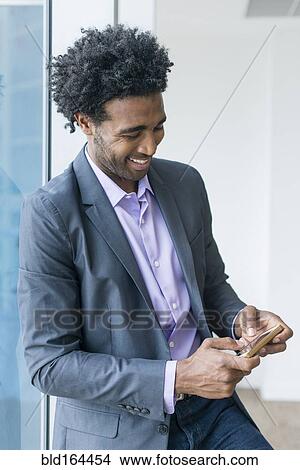 Picture - Hispanic businessman using cell phone in office. Fotosearch