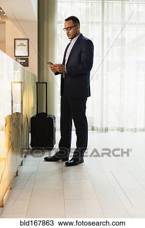 Hispanic businessman using cell phone at hotel front desk View Large Photo Image Stock Image - Hispanic businessman using cell phone at hotel front desk. Fotosearch
