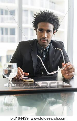 Stock Photo - Hispanic businessman using cell phone at conference table. Fotosearch