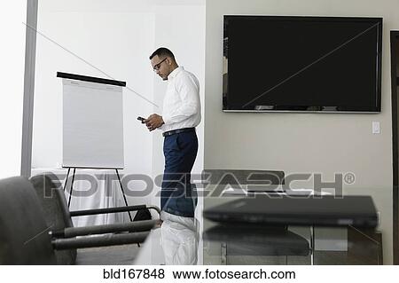 Hispanic businessman using cell phone in conference room View Large Photo Image Stock Photo - Hispanic businessman using cell phone in conference room. Fotosearch