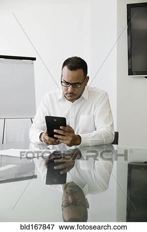 Hispanic businessman using digital tablet in office View Large Photo Image Stock Photo - Hispanic businessman using digital tablet in office. Fotosearch