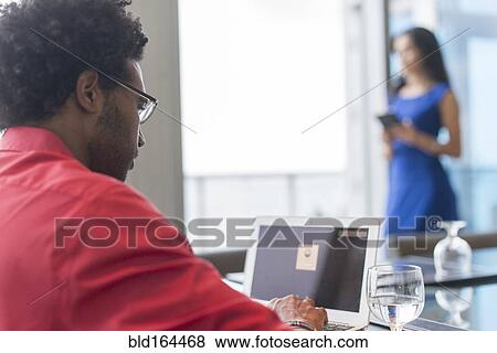 Stock Photo - Hispanic businessman using laptop at conference table. Fotosearch