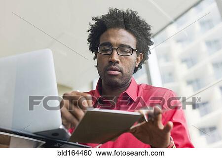 Hispanic businessman writing notes at glass office desk View Large Photo Image Stock Image - Hispanic businessman writing notes at glass office desk. Fotosearch