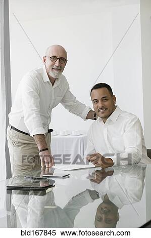 Stock Photography - Hispanic businessmen smiling in office meeting. Fotosearch