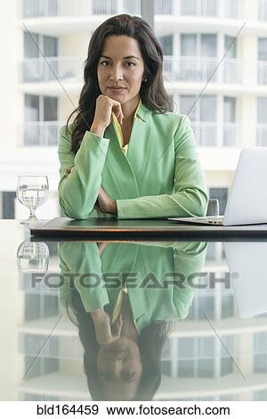 Hispanic businesswoman sitting at conference table View Large Photo Image Stock Photo - Hispanic businesswoman sitting at conference table. Fotosearch