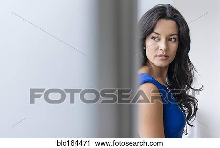 Stock Image - Hispanic businesswoman standing at office window. Fotosearch