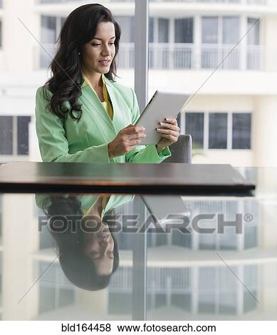 Stock Photo - Hispanic businesswoman using digital tablet at conference table. Fotosearch