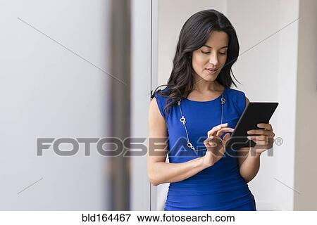 Stock Photo - Hispanic businesswoman using digital tablet in office. Fotosearch