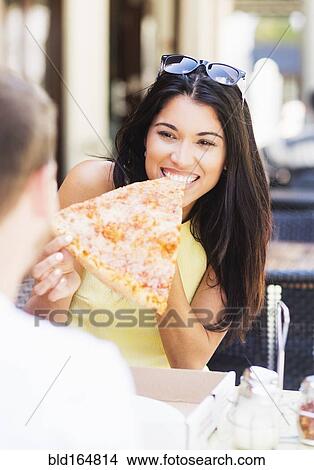 Picture - Hispanic couple eating pizza at cafe. Fotosearch