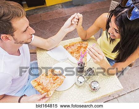 Stock Photography - Hispanic couple eating pizza at cafe. Fotosearch