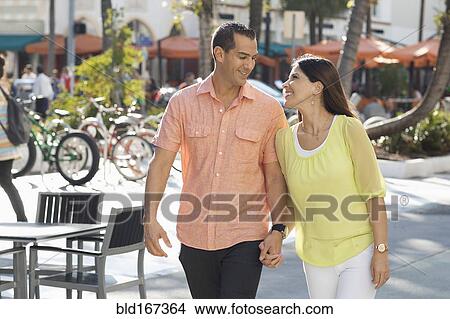 Picture - Hispanic couple holding hands on sidewalk. Fotosearch