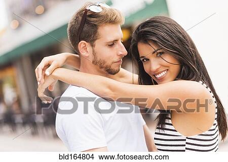 Picture - Hispanic couple hugging on sidewalk. Fotosearch