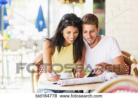 Stock Photo - Hispanic couple reading map at cafe. Fotosearch