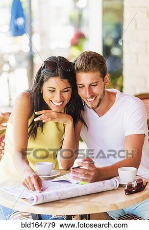 Stock Photo - Hispanic couple reading map at cafe. Fotosearch