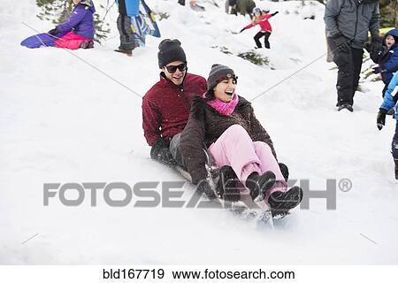 Hispanic couple sledding on snowy hillside View Large Photo Image Stock Photo - Hispanic couple sledding on snowy hillside. Fotosearch