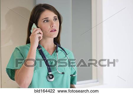 Stock Image - Hispanic doctor talking on cell phone in hospital. Fotosearch