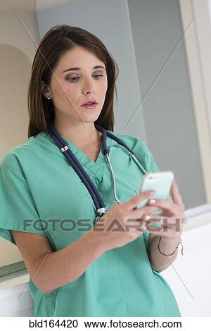 Stock Image - Hispanic doctor using cell phone in hospital. Fotosearch