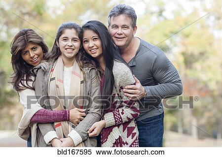 Stock Photography - Hispanic family hugging outdoors. Fotosearch