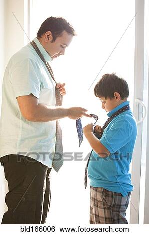Stock Photograph - Hispanic father showing son how to tie necktie. Fotosearch