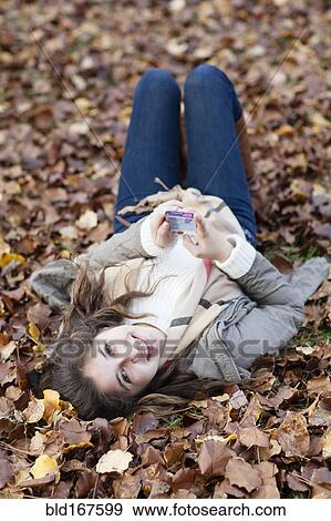 Stock Photo - Hispanic girl laying in autumn leaves. Fotosearch
