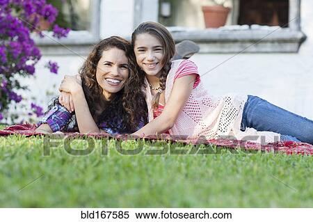 Stock Photography - Hispanic mother and daughter hugging in backyard. Fotosearch