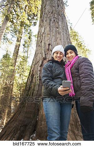 Hispanic mother and daughter taking selfie in forest View Large Photo Image Stock Photography - Hispanic mother and daughter taking selfie in forest. Fotosearch