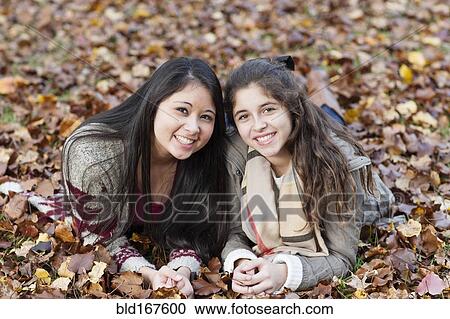 Hispanic sisters laying in autumn leaves View Large Photo Image Stock Image - Hispanic sisters laying in autumn leaves. Fotosearch