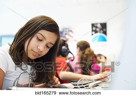 Stock Photo - Hispanic student working at desk in classroom. Fotosearch