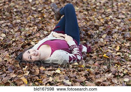 Stock Photo - Hispanic teenage girl laying in autumn leaves. Fotosearch