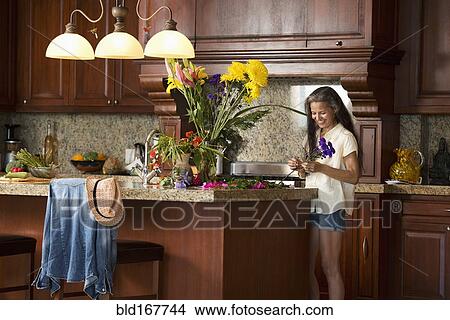 Hispanic woman arranging flowers in kitchen View Large Photo Image Picture - Hispanic woman arranging flowers in kitchen. Fotosearch