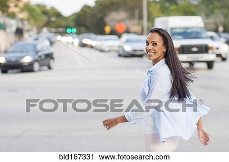 Stock Image - Hispanic woman crossing city street. Fotosearch
