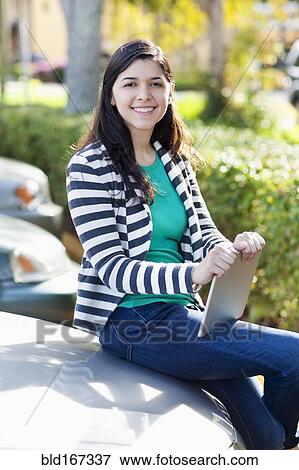 Stock Photo - Hispanic woman holding digital tablet in parking lot. Fotosearch