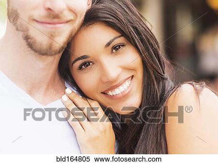 Stock Photography - Hispanic woman hugging boyfriend on sidewalk. Fotosearch