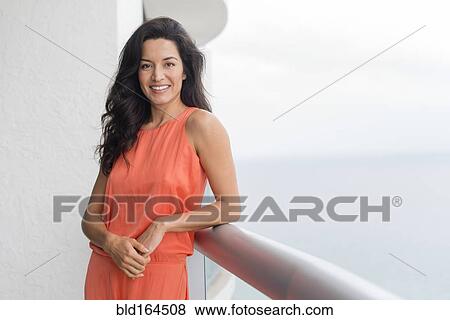 Stock Photo - Hispanic woman leaning on balcony. Fotosearch