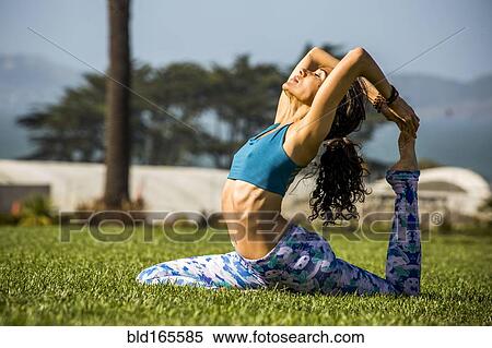 Stock Photography - Hispanic woman practicing yoga in park. Fotosearch
