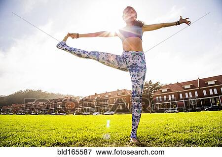 Stock Photo - Hispanic woman practicing yoga in urban park. Fotosearch