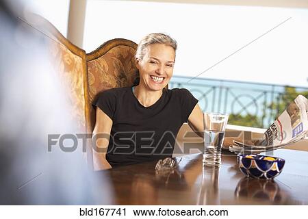 Hispanic woman reading newspaper at table View Large Photo Image Stock Image - Hispanic woman reading newspaper at table. Fotosearch