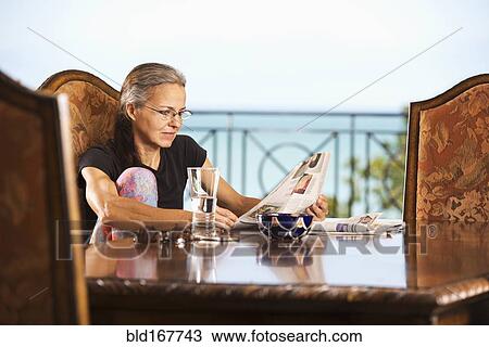 Hispanic woman reading newspaper at table View Large Photo Image Stock Image - Hispanic woman reading newspaper at table. Fotosearch