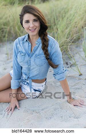Stock Photo - Hispanic woman sitting on beach. Fotosearch