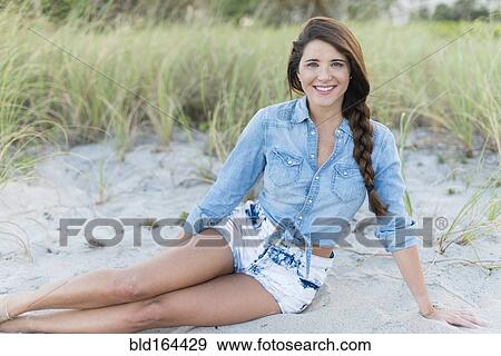 Stock Photo - Hispanic woman sitting on beach. Fotosearch