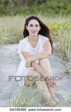 Stock Photo - Hispanic woman sitting on beach. Fotosearch