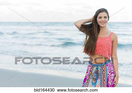 Stock Image - Hispanic woman standing on beach. Fotosearch