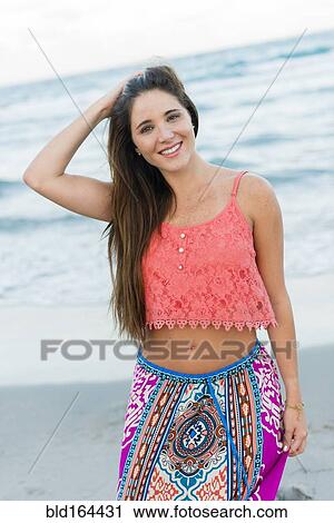 Stock Image - Hispanic woman standing on beach. Fotosearch