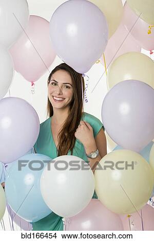 Picture - Hispanic woman standing with balloons. Fotosearch