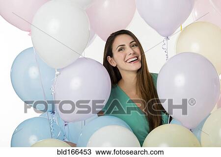 Stock Image - Hispanic woman standing with balloons. Fotosearch