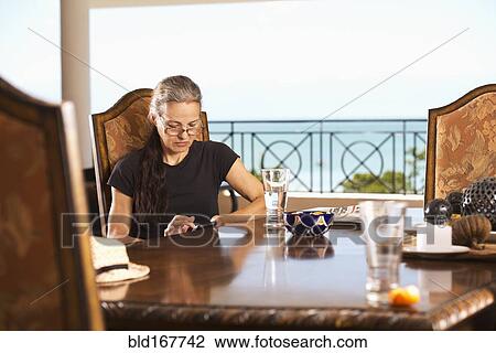 Hispanic woman using cell phone at table View Large Photo Image Stock Image - Hispanic woman using cell phone at table. Fotosearch