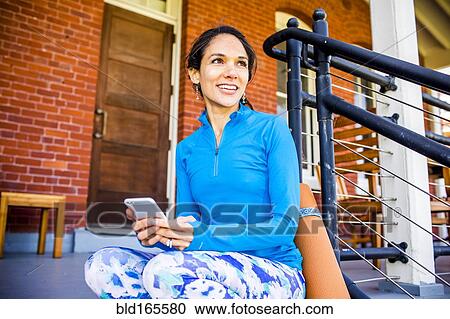 Hispanic woman using cell phone on porch View Large Photo Image Stock Image - Hispanic woman using cell phone on porch. Fotosearch