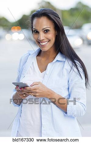Hispanic woman using cell phone outdoors View Large Photo Image Stock Image - Hispanic woman using cell phone outdoors. Fotosearch