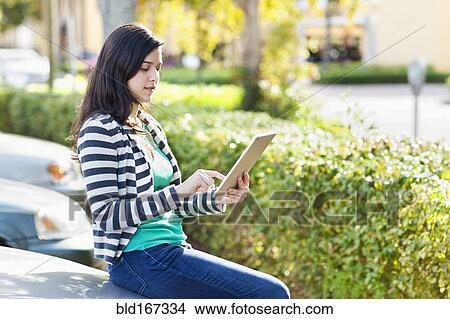 Picture - Hispanic woman using digital tablet in parking lot. Fotosearch